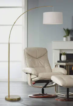 360 Lighting Cora arc floor lamp with brass finish and white linen drum shade in a living room corner